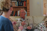 BG Energy trust image of an elderly man sitting down talking to a lady and drinking tea